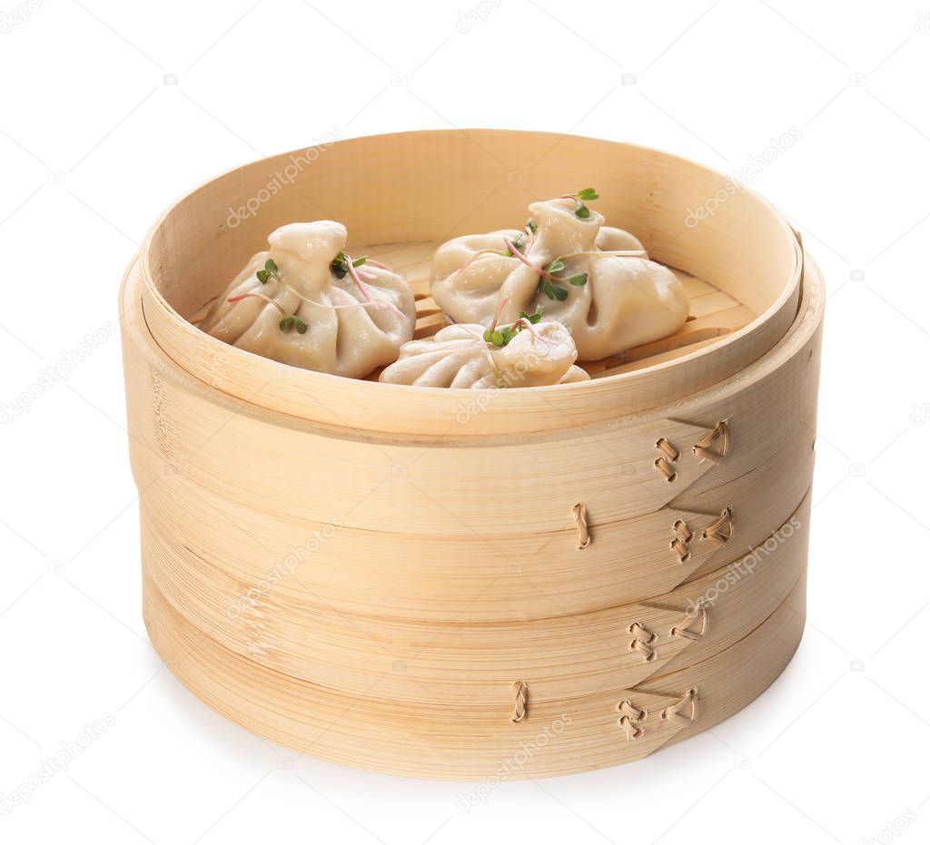 Bamboo steamer with tasty baozi dumplings on white background