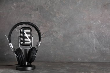 Retro mikrofon ve kulaklık tabloda gri bir arka plana dayanır. Metin için yer