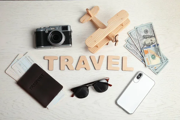 Επίπεδη lay σύνθεση με ταξίδια, φωτογραφική μηχανή και διαβατήριο σε φόντο ξύλινη λέξη. Τουριστικό πρακτορείο — Φωτογραφία Αρχείου