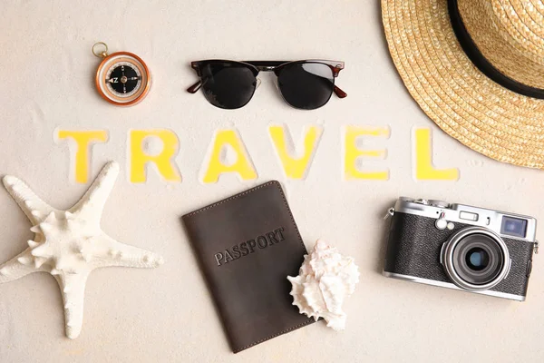 Plat leggen samenstelling met verschillende toeristische objecten en woord reizen op zand — Stockfoto