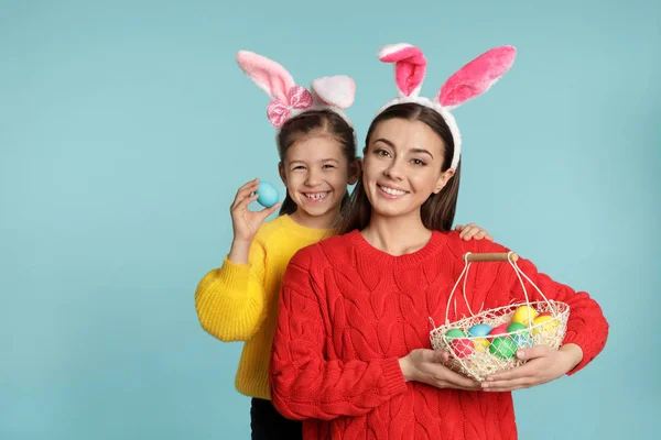 母女在兔子耳朵头带与复活节彩蛋在颜色背景 — 图库照片