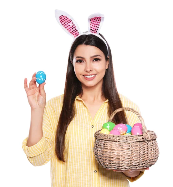 美丽的妇女在兔子耳朵头带拿篮子与复活节彩蛋在白色背景 — 图库照片