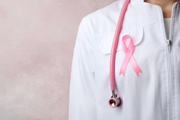 Доктор с розовой лентой и стетоскопом на цветном фоне, место для текста. Осознание рака молочной железы — стоковое фото