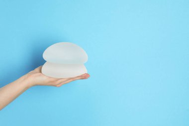 Silikon silikon tutan kadın ve göğüs büyütme renk arka plan, metin için yer için. Kozmetik cerrahi