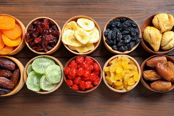 Cuencos con diferentes frutas secas sobre fondo de madera, puesta plana. Estilo de vida saludable — Foto de Stock