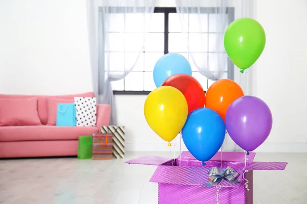 Gift box with bright air balloons in living room. Space for text — Stock Photo, Image