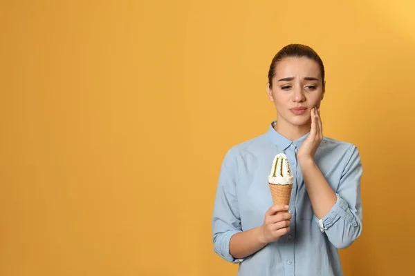 情绪年轻的女人与敏感的牙齿和冰淇淋的颜色背景。文本的空间 — 图库照片