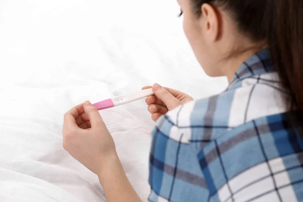 Jovem com teste de gravidez na cama, close-up. Ginecologia e parto — Fotografia de Stock