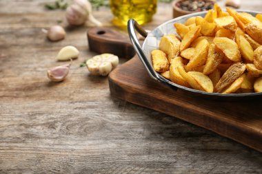 Tava ile lezzetli patates dilimleri ahşap masa üzerinde pişmiş. Metin için yer