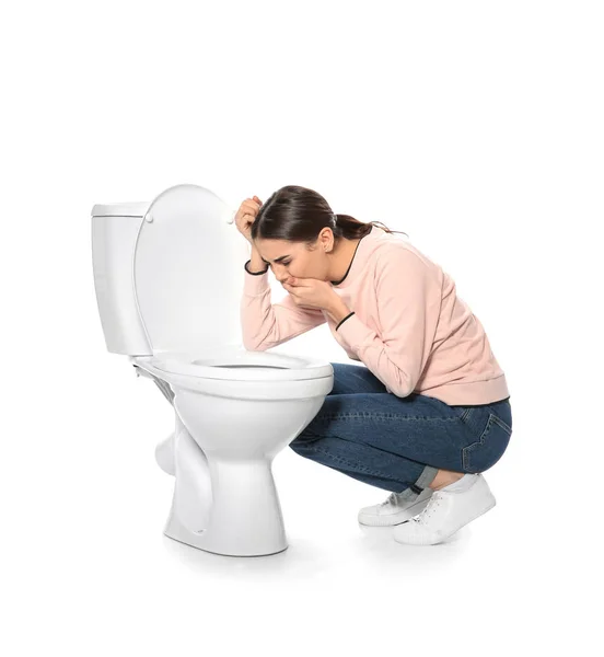 Молода жінка, що страждає нудотою біля туалету, ізольована на білому — стокове фото