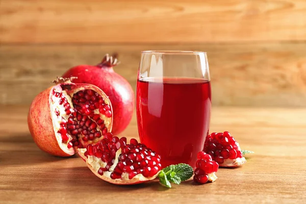 Vaso de jugo de granada y frutas frescas sobre mesa de madera —  Fotos de Stock