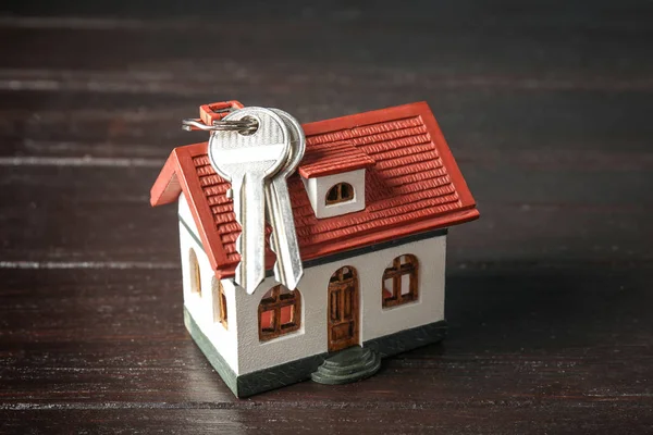 Modelo de casa y llaves sobre fondo de madera — Foto de Stock