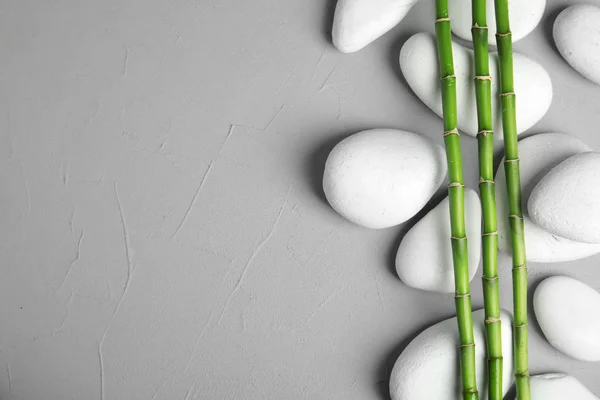 Zen stenen en bamboe op grijze achtergrond, bovenaanzicht met ruimte voor tekst — Stockfoto