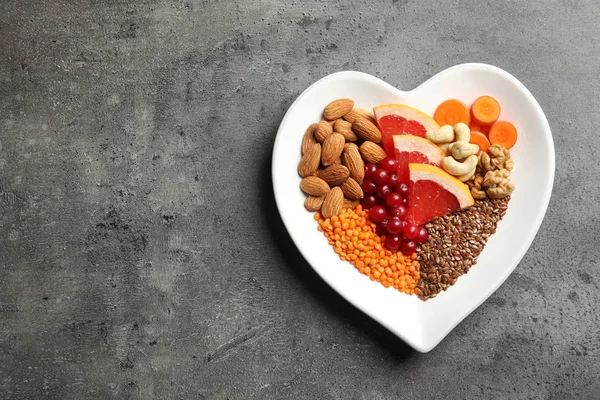 Plate with heart-healthy diet products on grey background, top view. Space for text