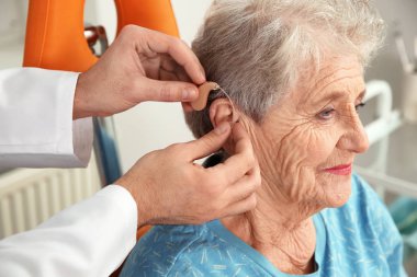 Klinikte üst düzey hastanın kulağına işitme cihazı koyarak otolaryngologist