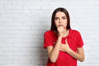 Güzel genç kadın tuğla duvar yakın öksürük. Metin alanı