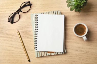 Tahta arka planda defter, kahve ve bardaklarla düz kompozisyon