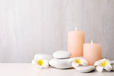 Zen taşları, ışık arka plana karşı masada yanan mumlar ve egzotik çiçekler. Metin alanı