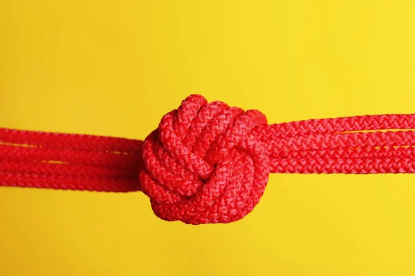 Cuerda roja con nudo sobre fondo de color — Foto de Stock