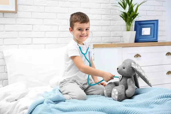 Söta barn spelar läkare med kvav leksak på säng i vårdavdelningen — Stockfoto