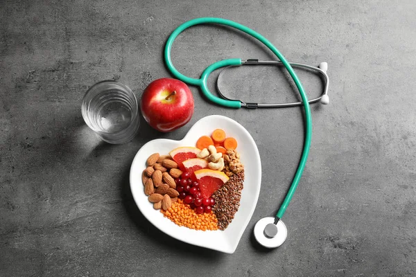 Плоская композиция с пластиной продуктов для здорового питания сердца на сером фоне — стоковое фото
