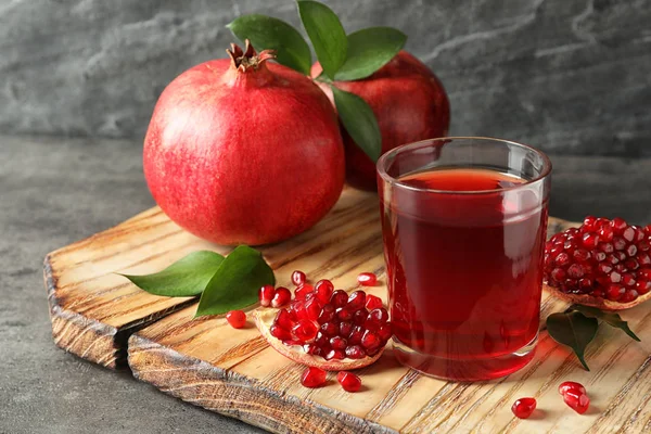 Bicchiere di succo di melograno e frutta fresca su tavola di legno su sfondo grigio — Foto Stock