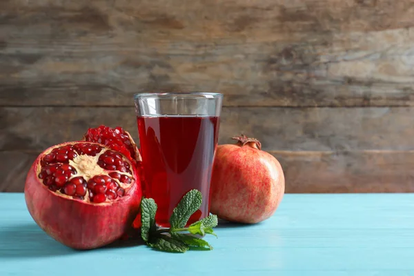 Vaso de jugo de granada y frutas frescas sobre mesa sobre fondo de madera, espacio para texto —  Fotos de Stock