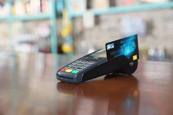 Credit card machine for non cash payment on wooden counter in cafe. Space for text