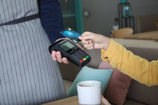 Client using credit card machine for non cash payment in cafe, closeup