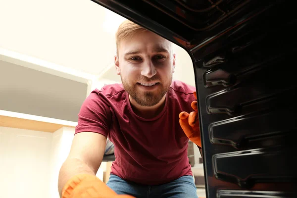 Joven limpiando horno en la cocina, vista desde el interior — Foto de Stock