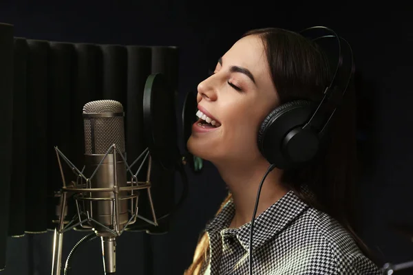 Young singer with microphone recording song in studio — Stock Photo, Image