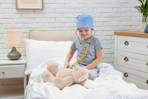 Симпатична дитина грає з лікарем з фаршированою іграшкою на ліжку в лікарняному палаті — стокове фото
