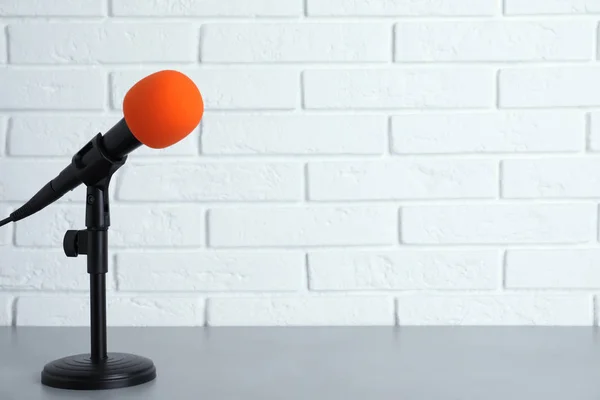 Nowoczesny mikrofon na stole w pobliżu mur z cegły. Miejsca na tekst — Zdjęcie stockowe