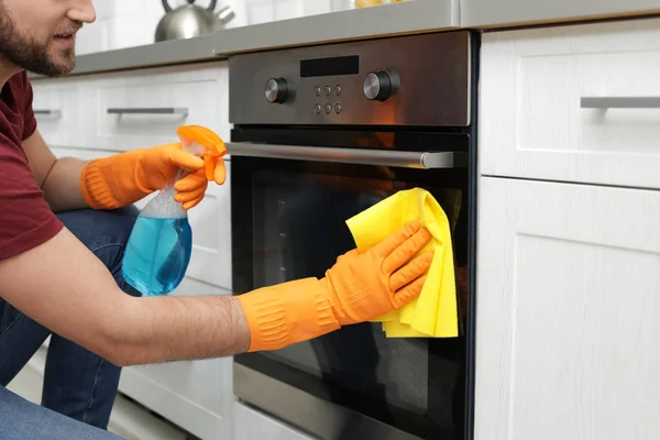 Joven limpieza horno con trapo y detergente en la cocina, primer plano — Foto de Stock