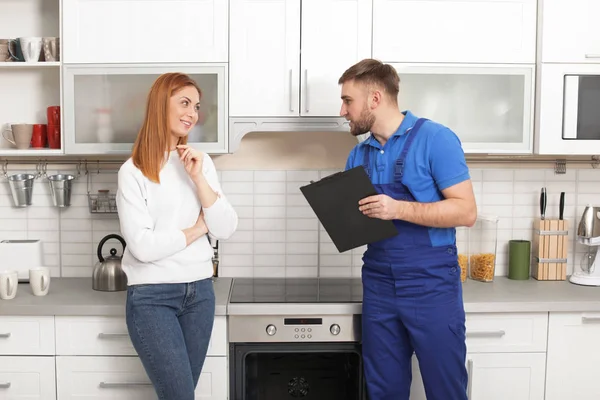 Ibu rumah tangga dengan tukang reparasi dekat oven modern di dapur — Stok Foto