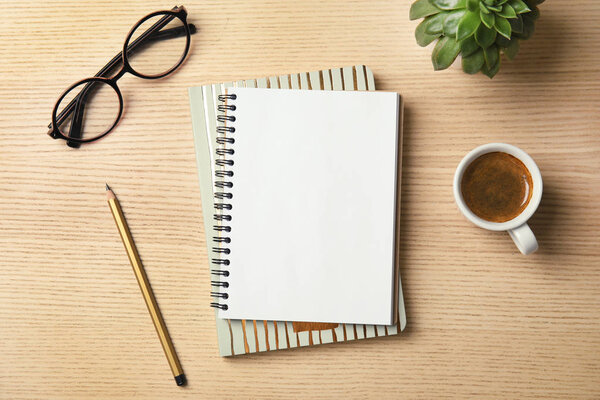 Flat lay composition with notebooks, coffee and glasses on wooden background