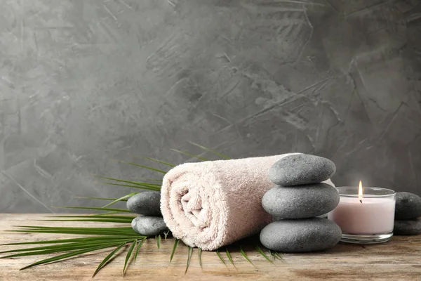 Composición con piedras zen, toalla y vela sobre mesa sobre fondo gris. Espacio para texto —  Fotos de Stock