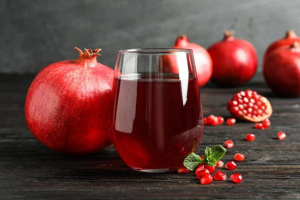 Bicchiere di succo di melograno e frutta fresca sul tavolo sullo sfondo grigio — Foto Stock