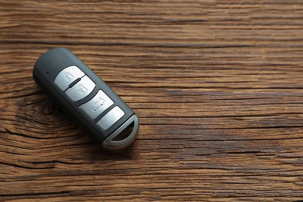 Remote car key on wooden background, top view. Space for text