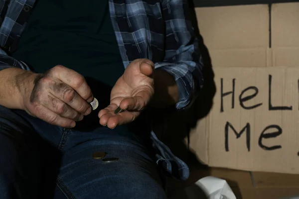 Homem sênior pobre contando moedas perto de cartão sinal AJUDA-ME, close-up — Fotografia de Stock