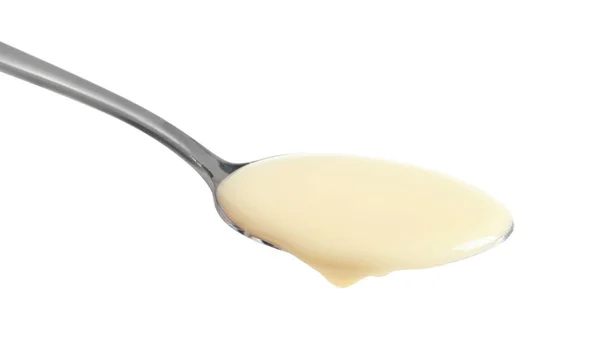 Cuchara con leche condensada sobre fondo blanco, primer plano. Productos lácteos — Foto de Stock