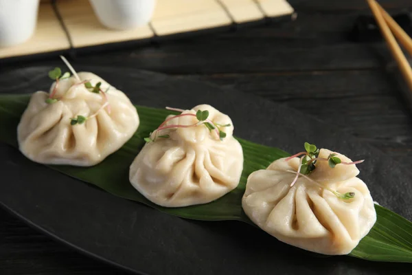 Slate plate with tasty baozi dumplings on table, closeup