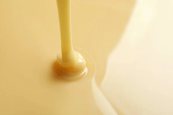 Saporito versando latte condensato come sfondo, spazio per il testo. Prodotti lattiero-caseari — Foto Stock