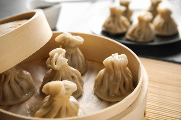 Bamboo steamer with tasty baozi dumplings on table, closeup