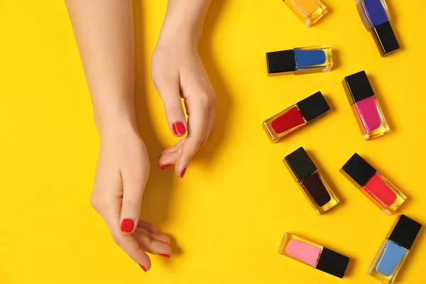 Mujer con manicura roja y botellas de esmalte de uñas sobre fondo de color, vista superior — Foto de Stock