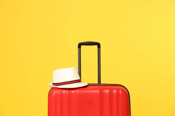 Světlý kufr s kloboukem na barevném pozadí — Stock fotografie