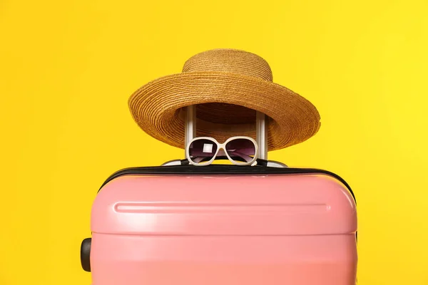 Elegante valigia con cappello e occhiali da sole su sfondo a colori — Foto Stock