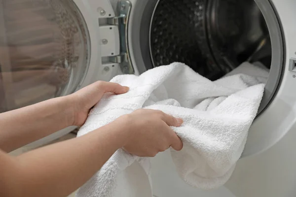 Kvinna tar ren handduk från tvätt maskin i tvätt stuga, närbild — Stockfoto