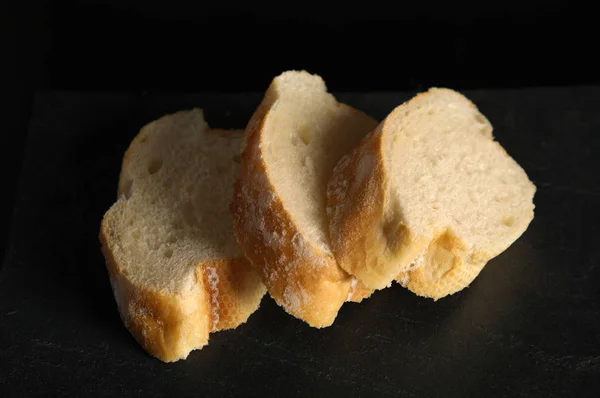 Sabroso pan de trigo en rodajas sobre mesa negra — Foto de Stock