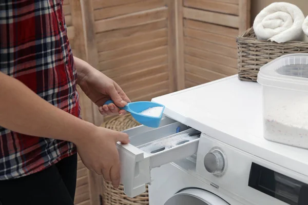 Woman pouring detergent powder into washing machine in laundry room, closeup — Stock Photo, Image